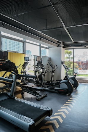 A gym with cardio machines, a treadmill, and a mirrored wall. - EVEN Hotel Hangzhou Yintai City by IHG (Hangzhou)
