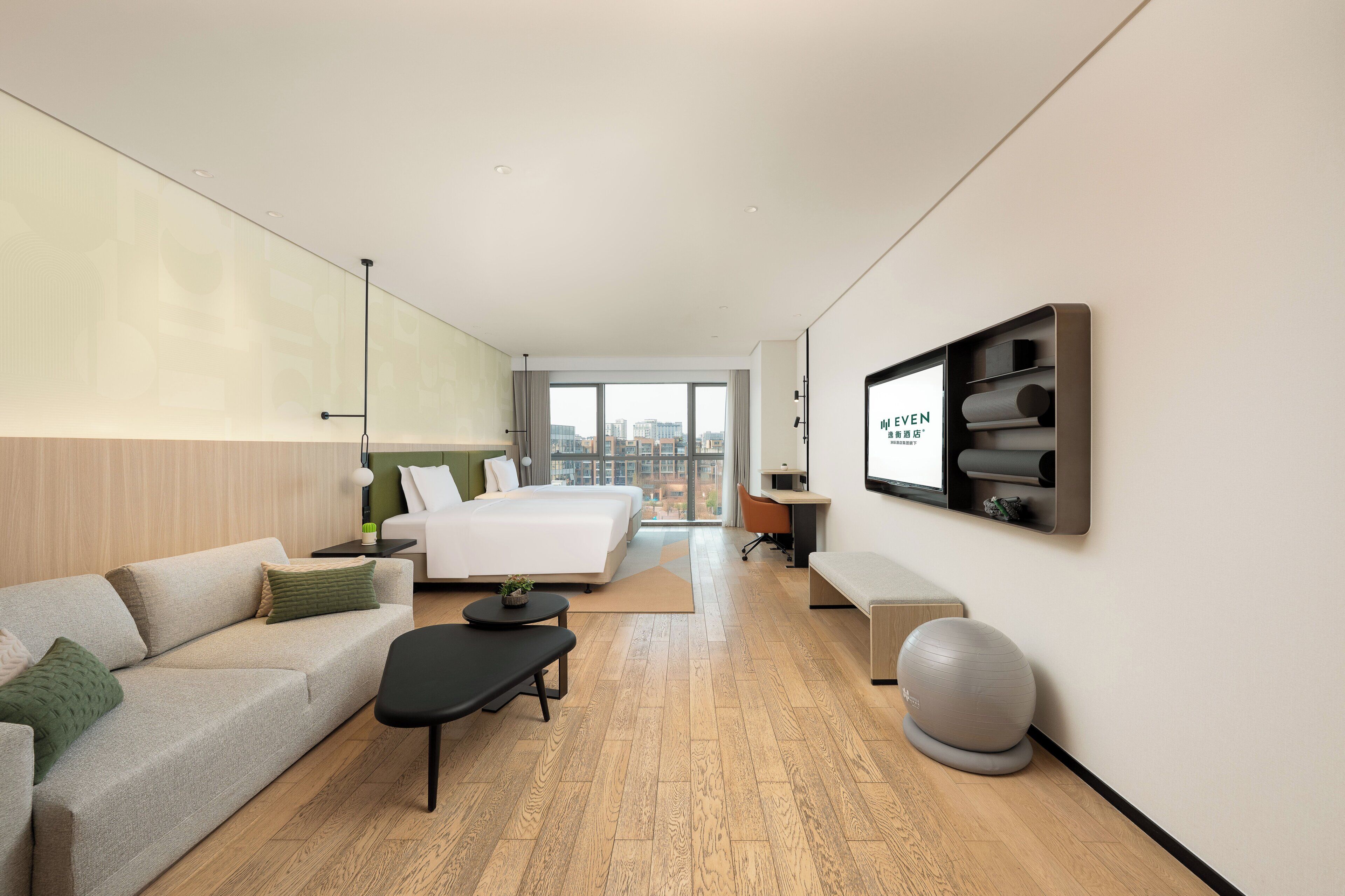 Una habitación de hotel moderna con una cama grande, un sofá, un escritorio y un televisor montado en la pared.