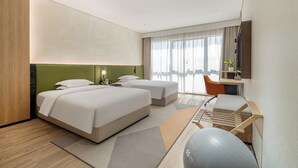 A modern hotel room with two beds, a desk, a chair, a treadmill, and a large window with curtains. - EVEN Hotel Hangzhou Yintai City by IHG (Hangzhou)