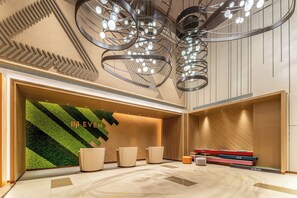 A modern hotel lobby with a green wall, a reception desk, and a seating area. - EVEN Hotel Hangzhou Yintai City by IHG (Hangzhou)