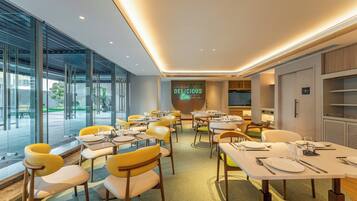 Un espace repas moderne avec des tables et des chaises, un mur en verre et un panneau lumineux au néon.