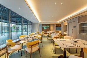 A modern dining area with tables and chairs, a glass wall, and a neon sign. - EVEN Hotel Hangzhou Yintai City by IHG (Hangzhou)
