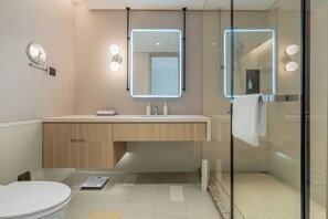 Un baño moderno con inodoro, tocador con espejo y zona de ducha.