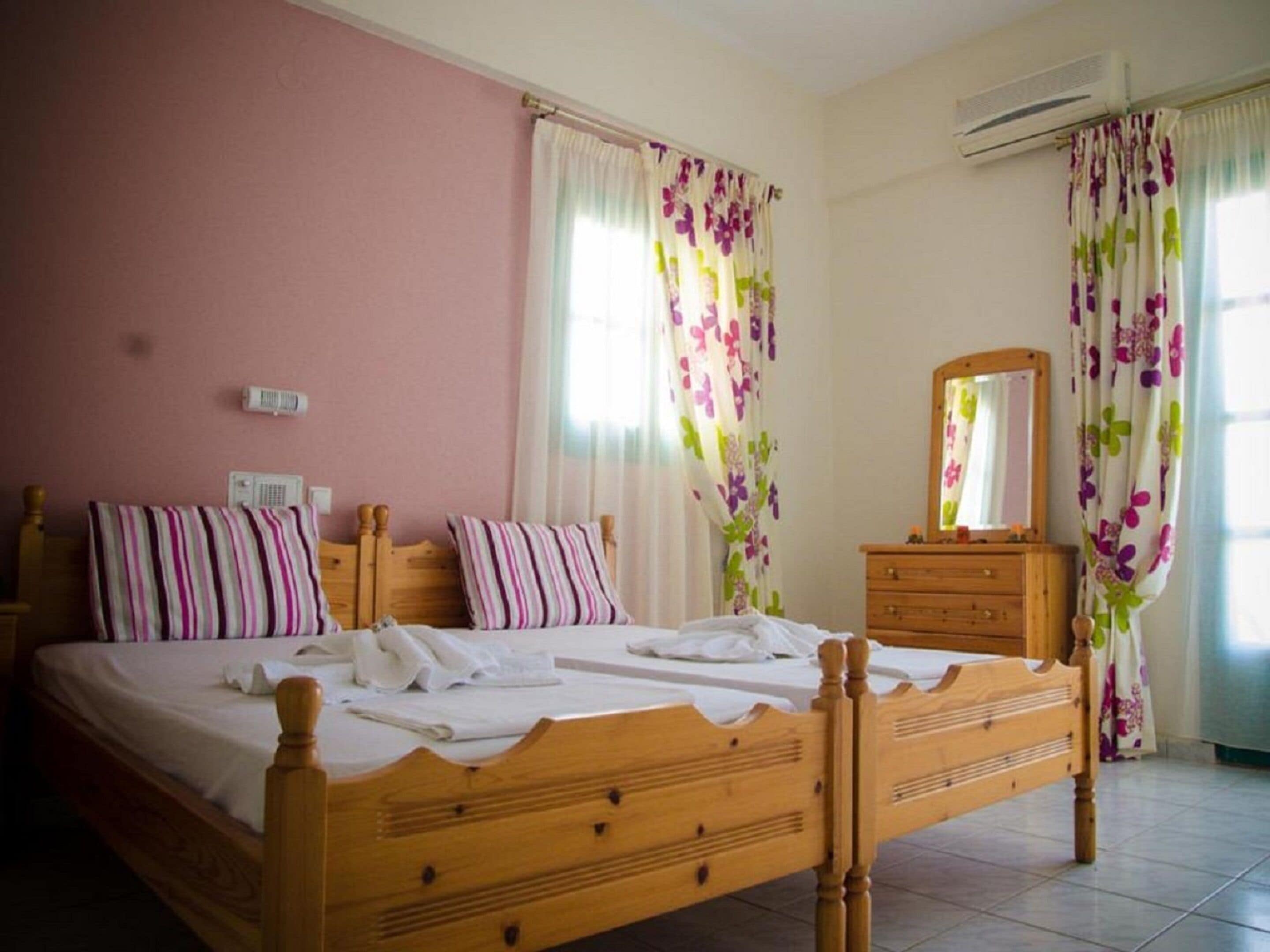 A bedroom with a wooden bed, a dresser, a mirror, and floral curtains.