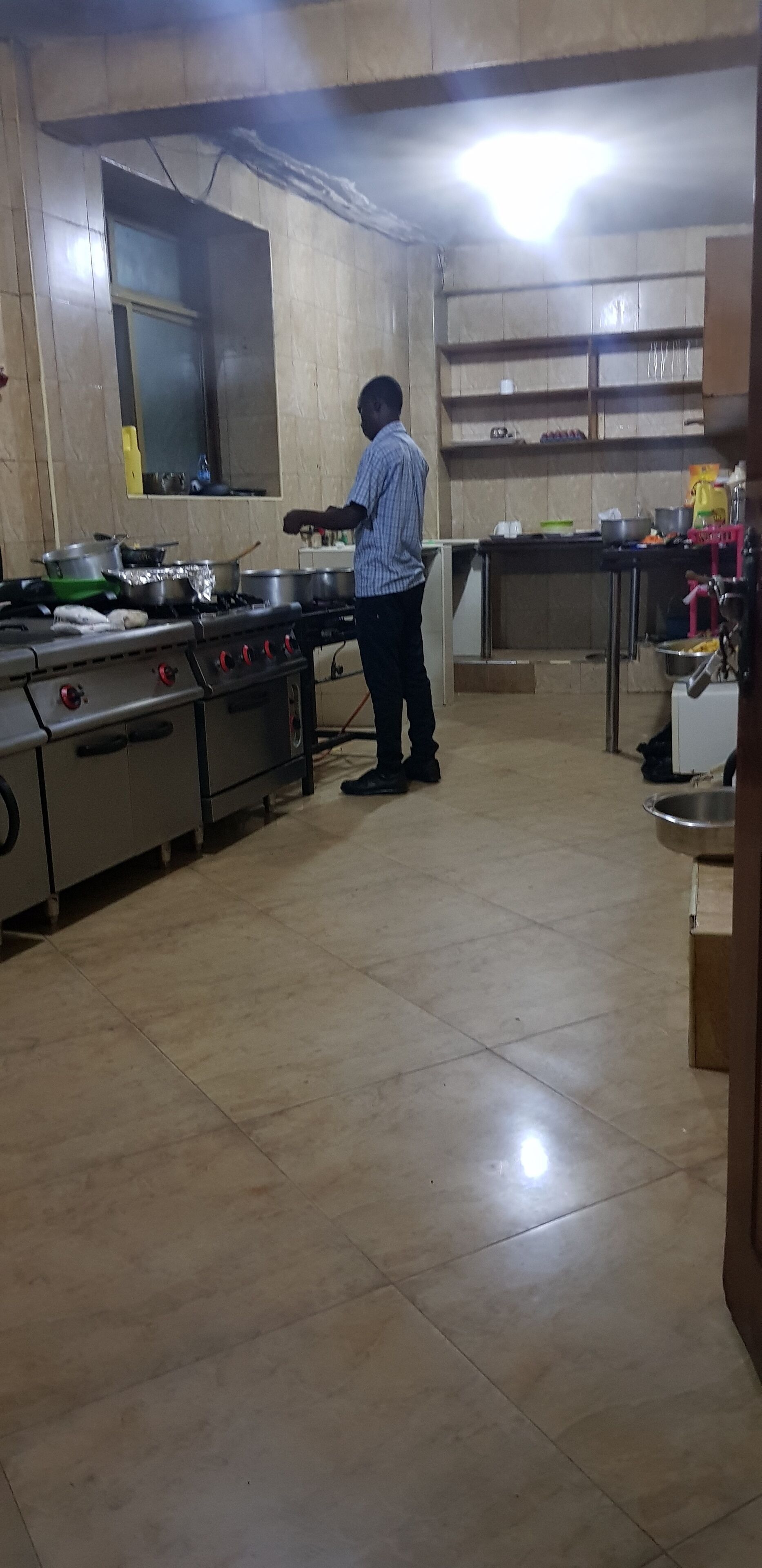 Cozinha com fogão, panelas e uma pessoa cozinhando.