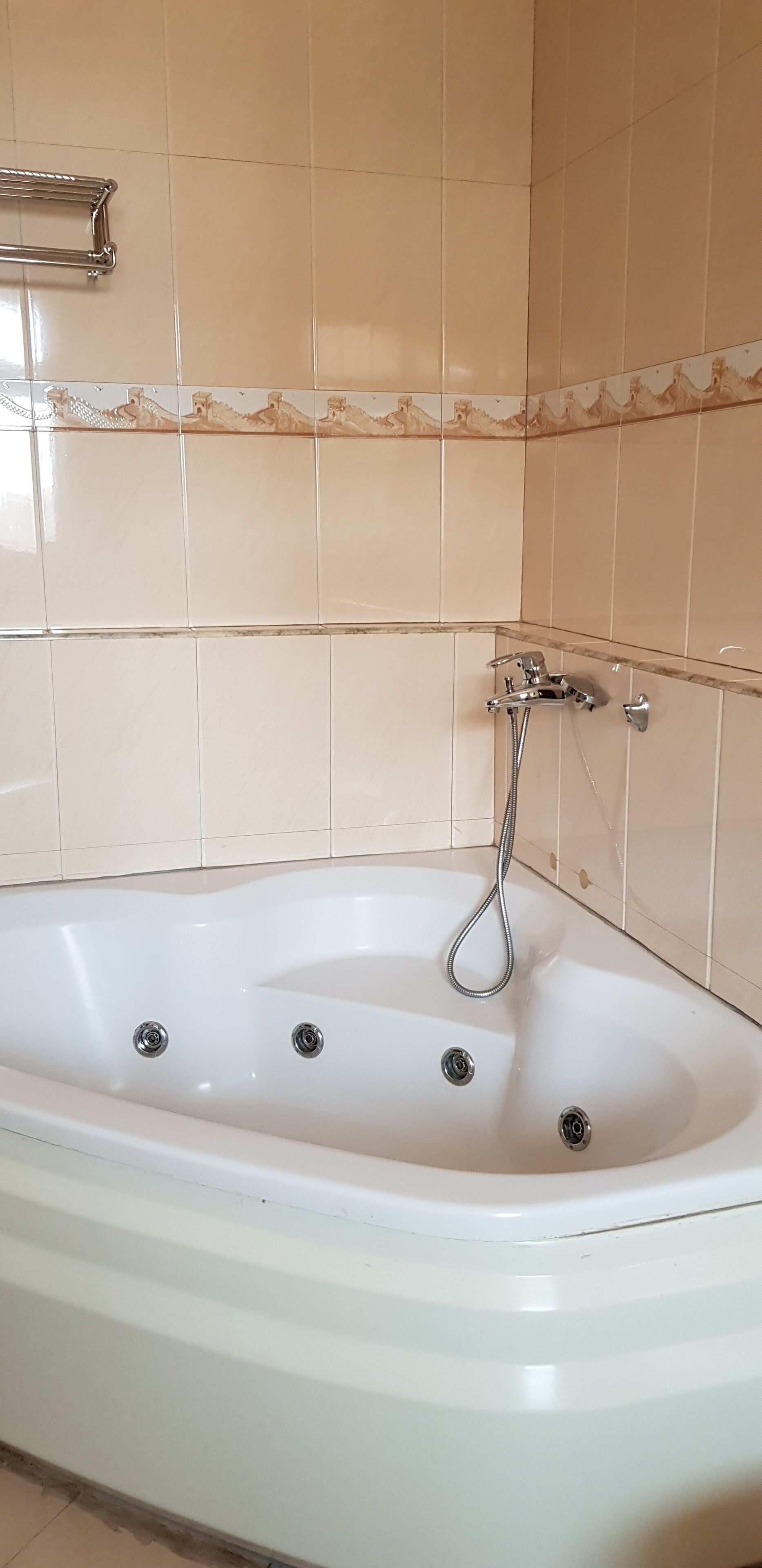 A bathroom with a white bathtub, a showerhead, and a towel rack.