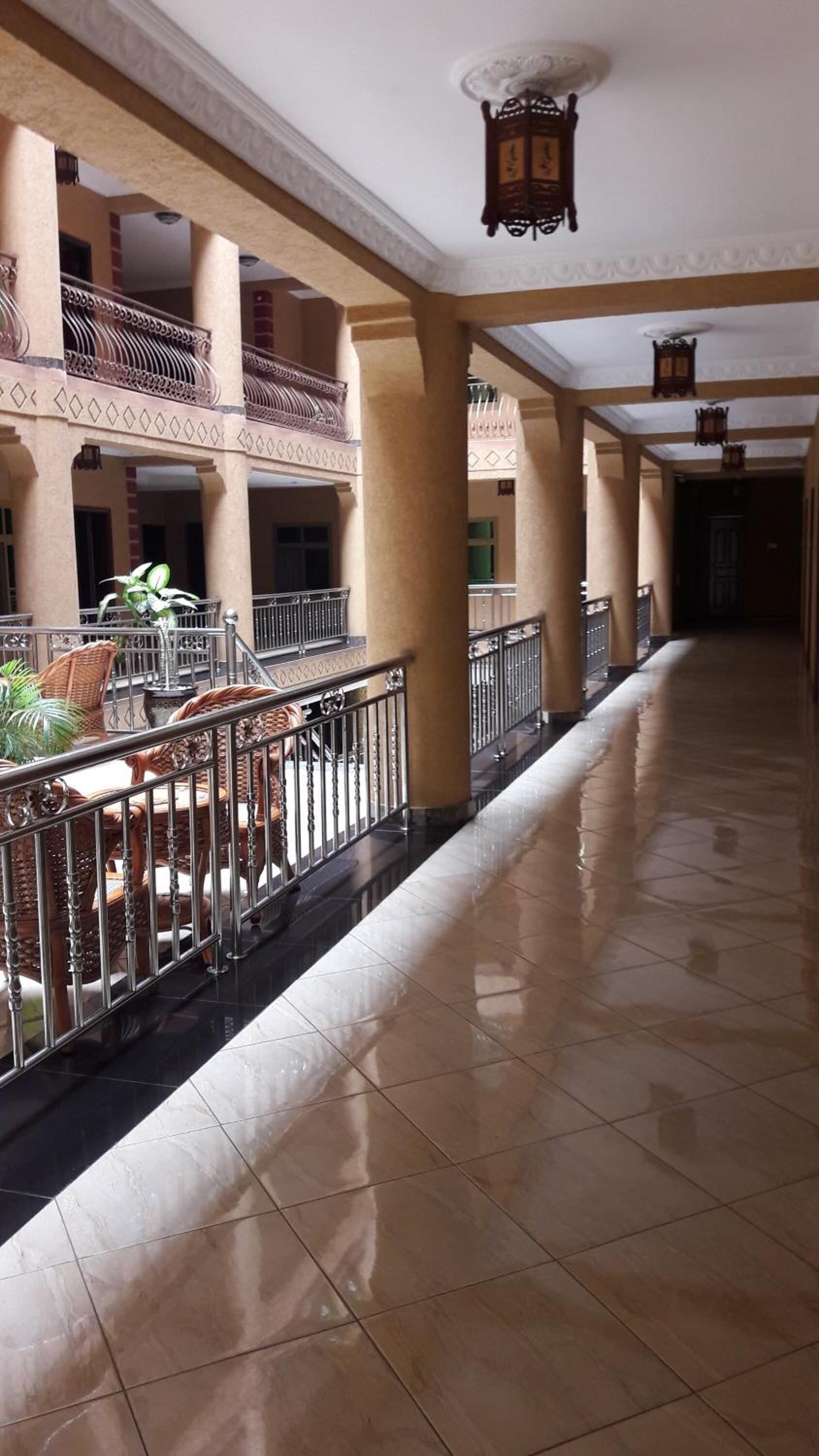 A spacious corridor with tiled flooring, a railing, and a hanging lantern.