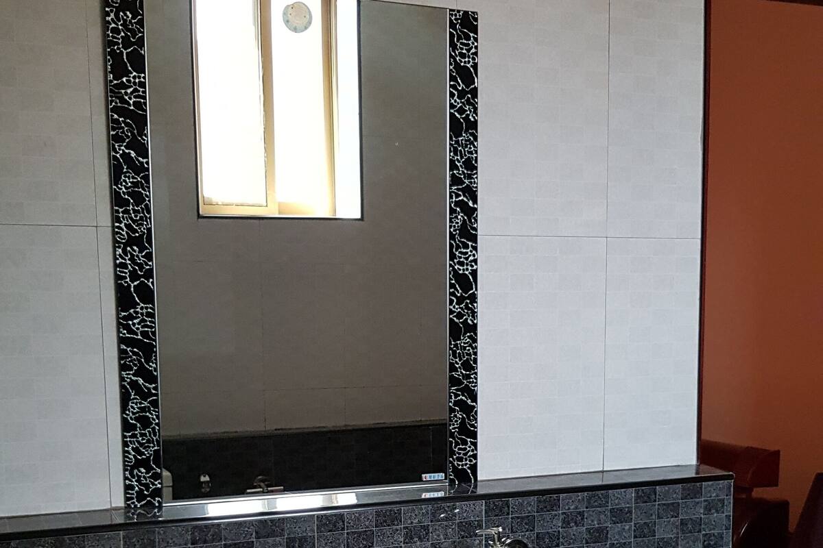 Une salle de bain avec un lavabo blanc, un miroir et une fenêtre.