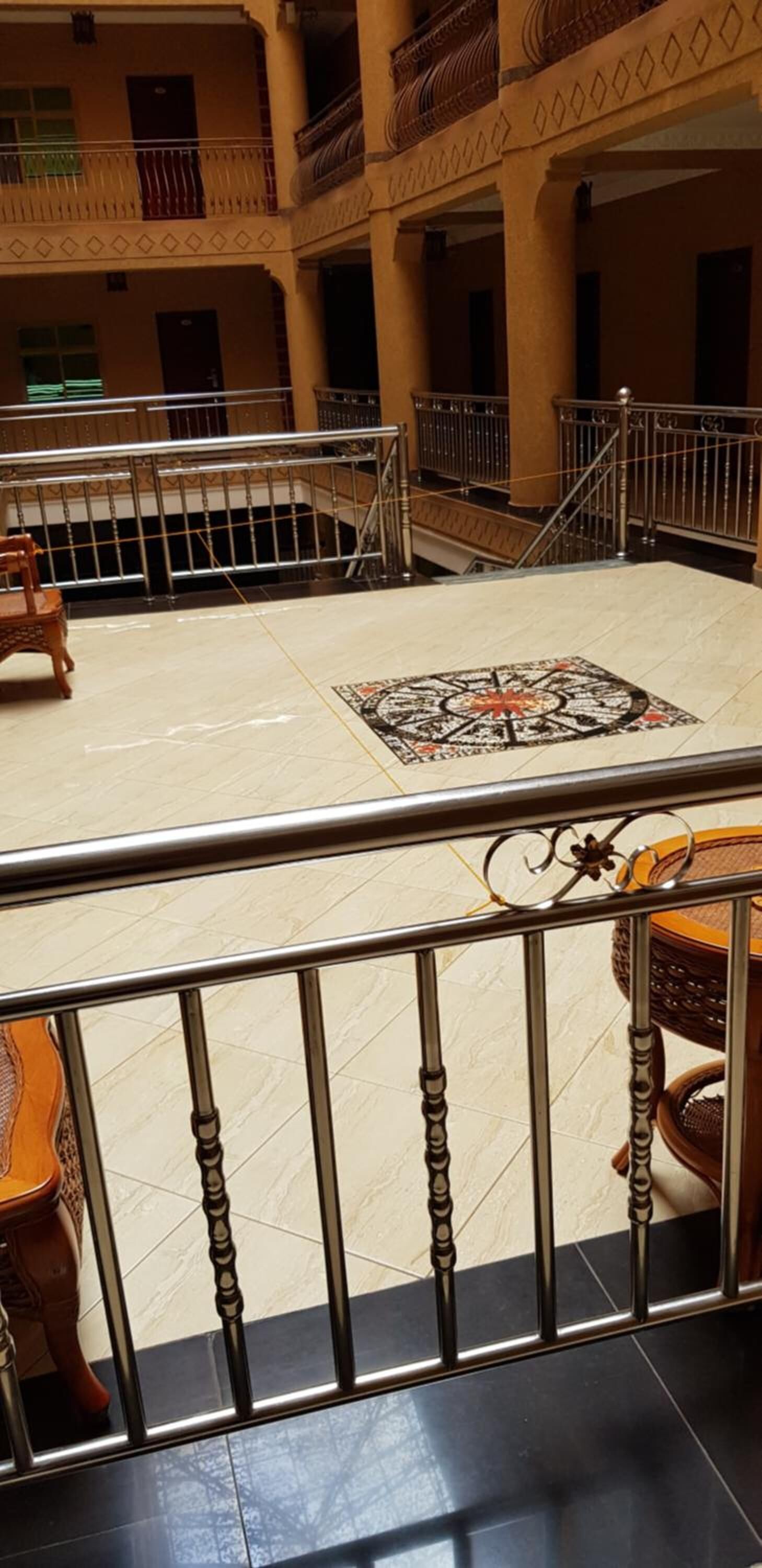 A spacious indoor area with a tiled floor, a decorative rug, and a wooden chair.