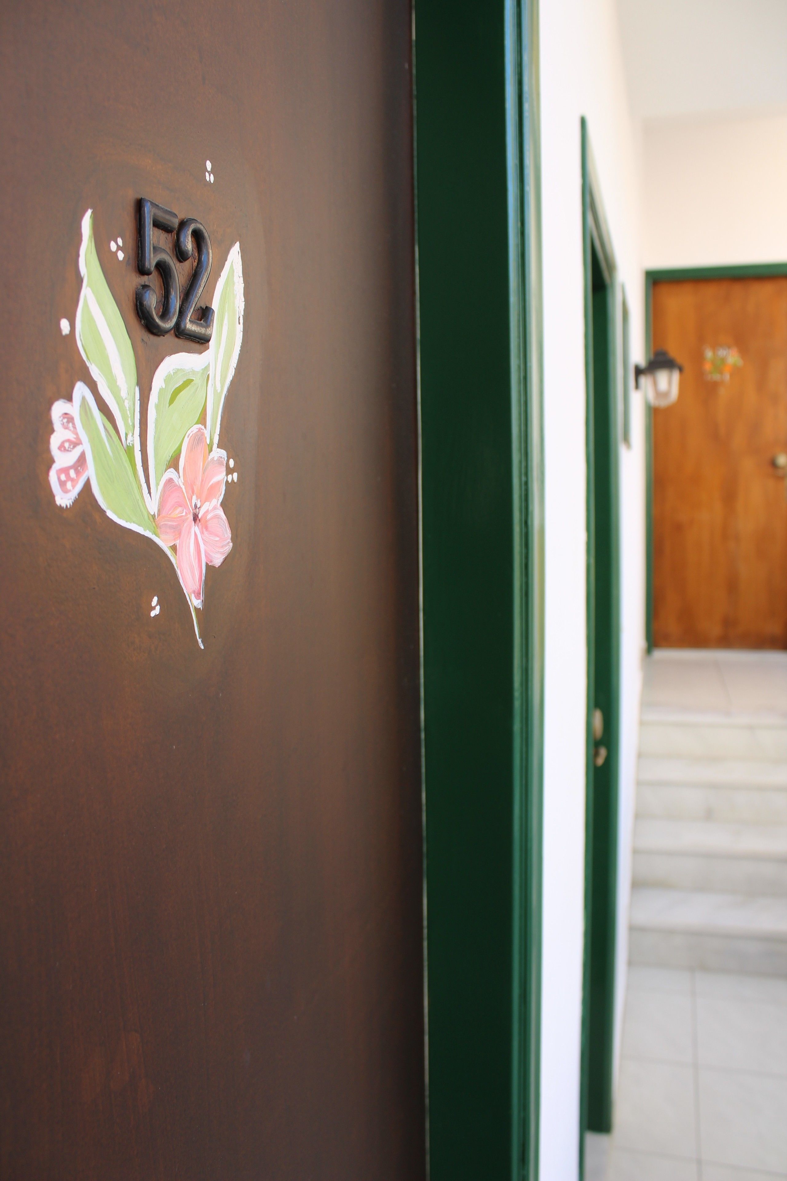 Un pasillo con una puerta marcada con el número 52 y un marco de puerta verde.