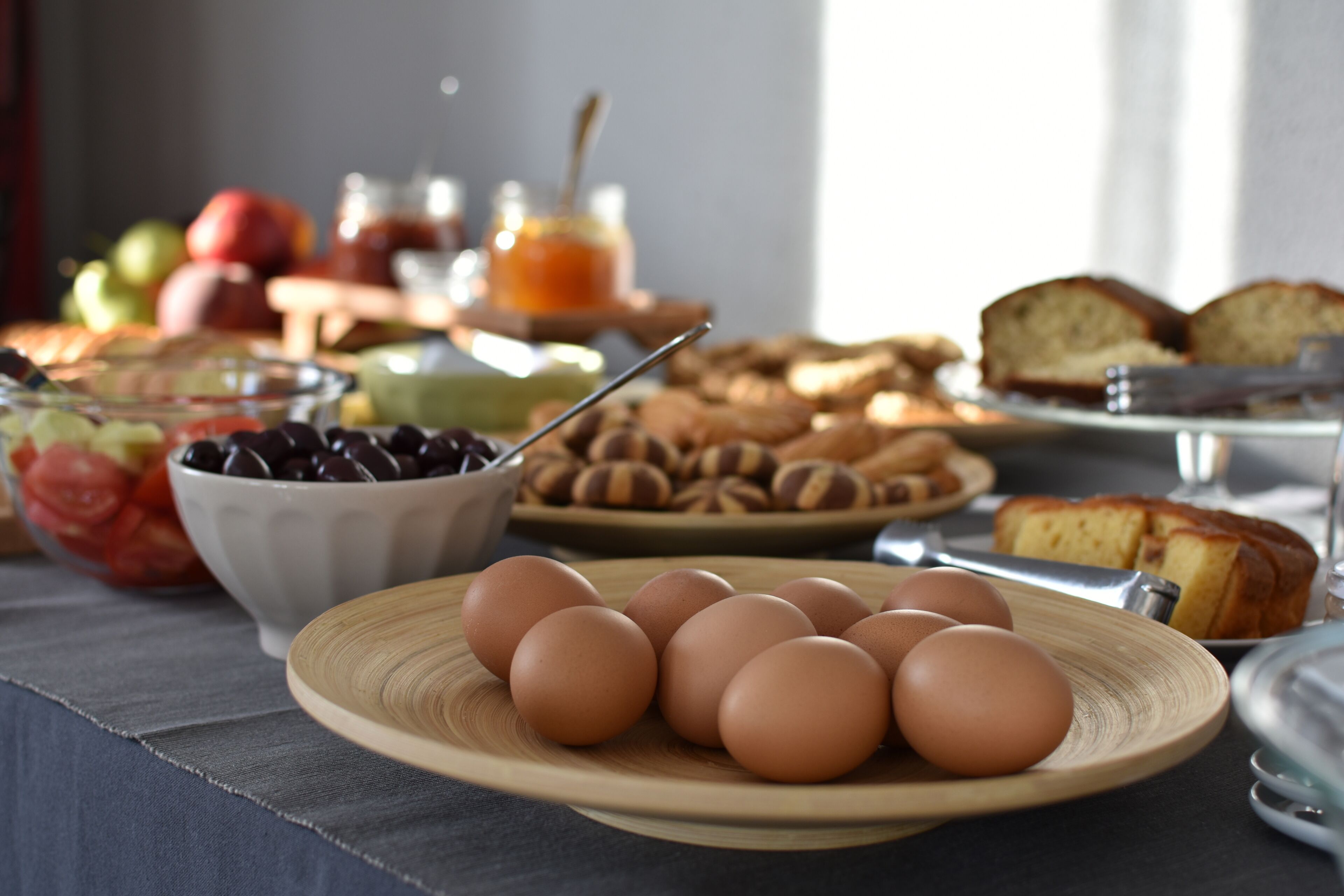A breakfast table with eggs, fruits, and pastries.