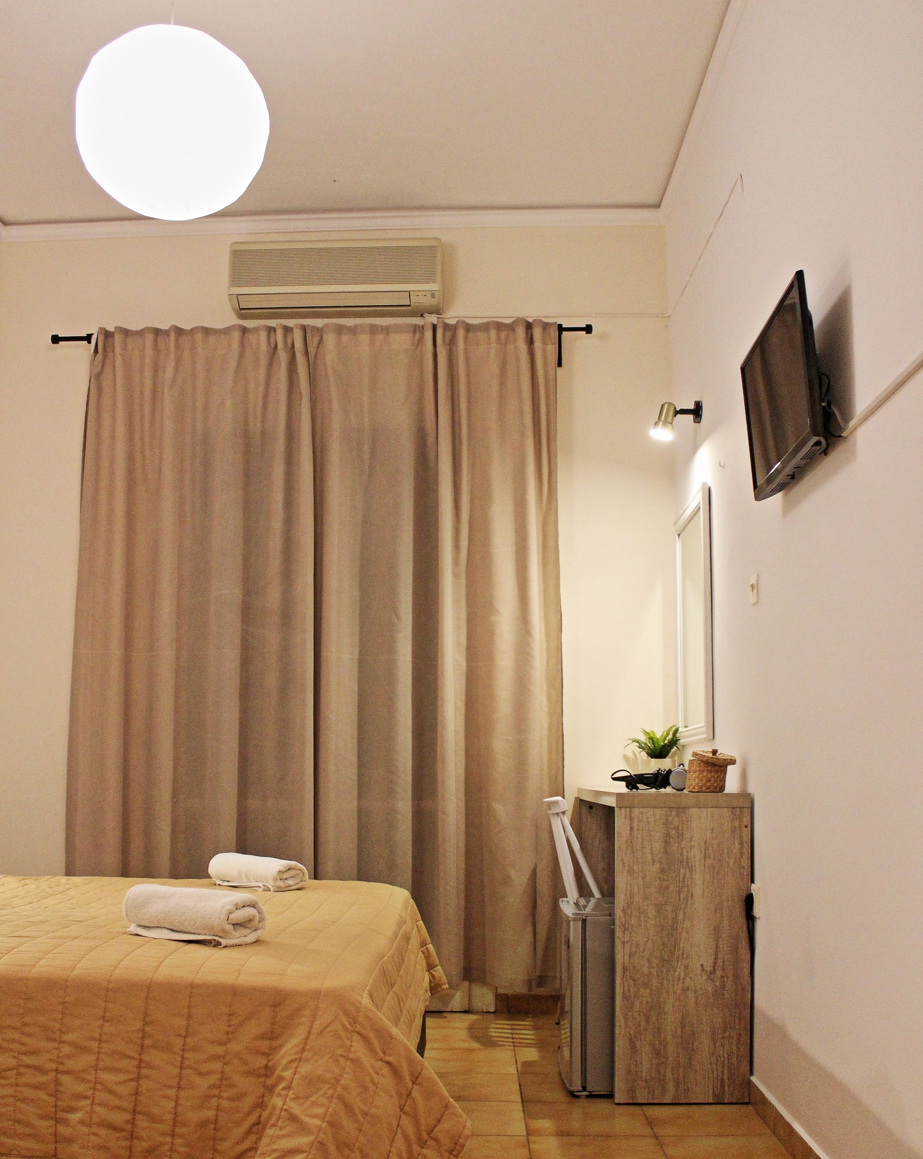 Een hotelkamer met een bed, een spiegel, een televisietoestel en een airconditioning.