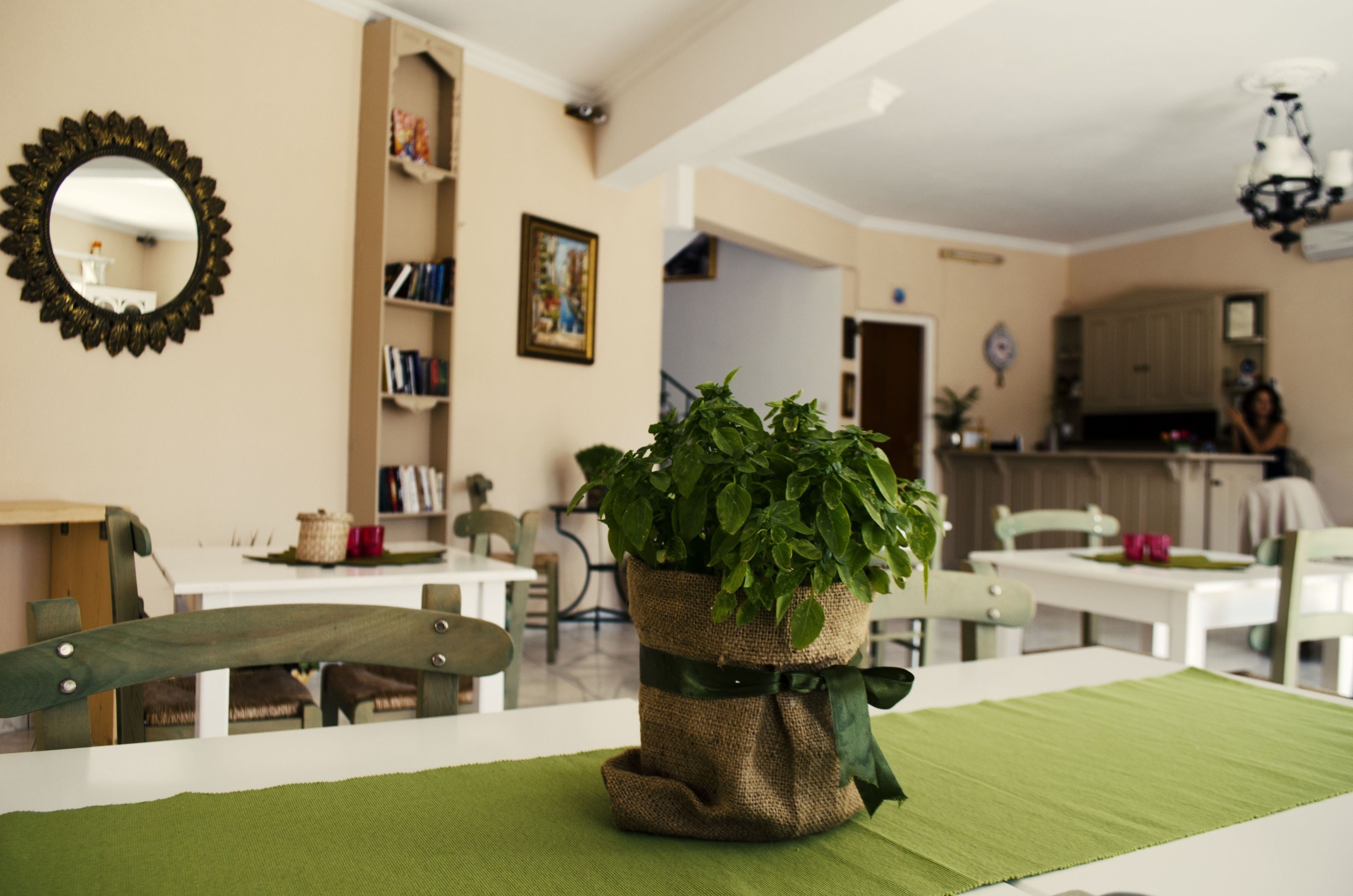 Een eethoek met een groene tafelkleed, een potplant en een spiegel aan de muur.