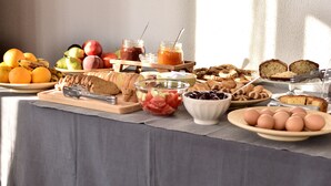 Un bufé de desayuno con frutas, pan, bollería y huevos.