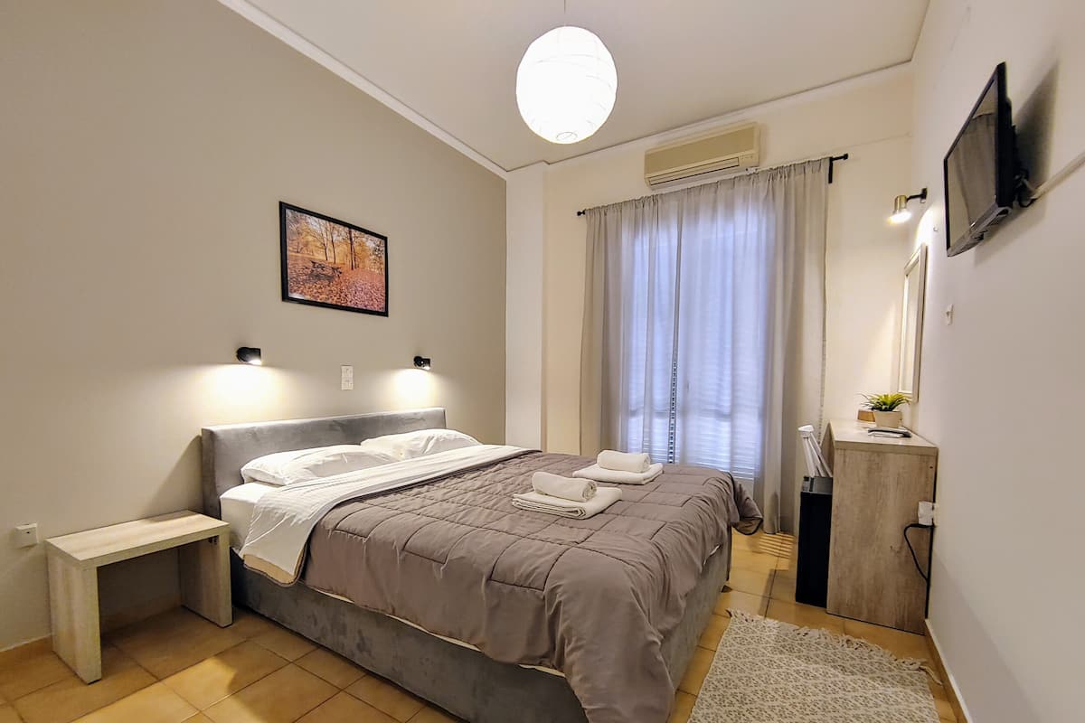 Een moderne slaapkamer met een bed, nachtkastje en een bureau met een spiegel.