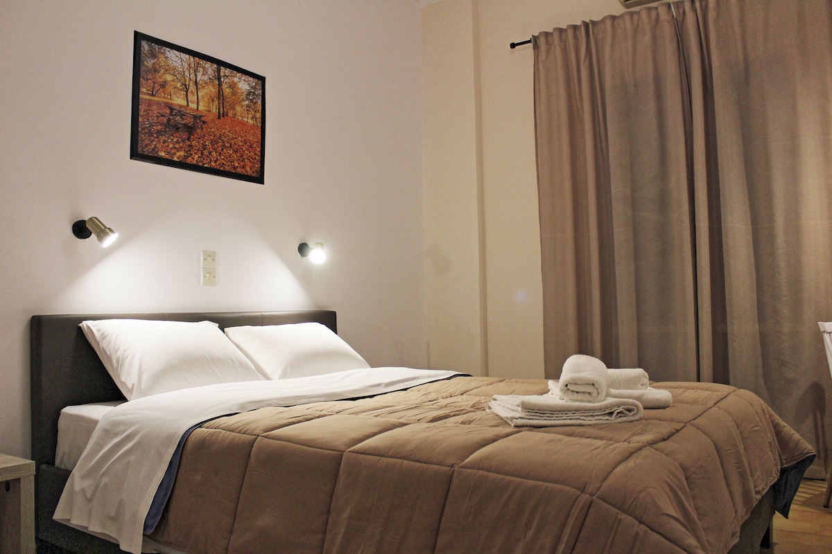 A neatly made bed with a brown bedspread, two white pillows, and a folded towel on the side.