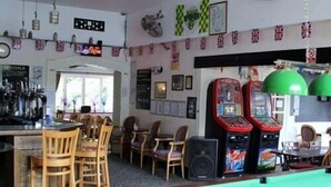 A bar area with pool tables, chairs, and arcade games. - The William IV (Norwich)