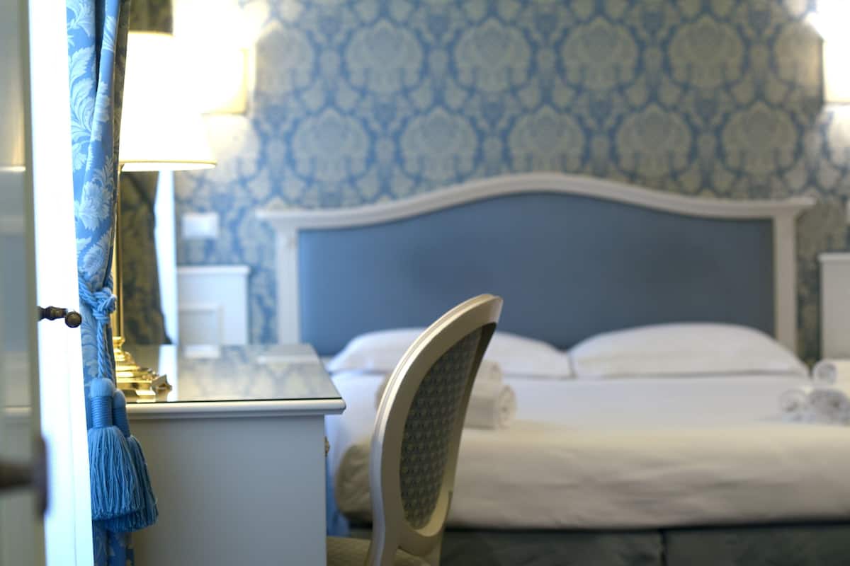 Une chambre à coucher avec un lit, une chaise, une table de chevet et une lampe.