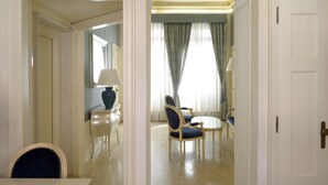 Quarto de hotel com área de refeições, uma cama e um banheiro visível através de um arco.