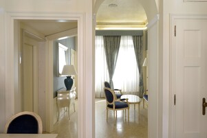 A hotel room with a dining area, a bed, and a bathroom visible through an archway.