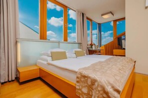 Quarto moderno com uma cama grande, um banco embutido e uma escrivaninha com cadeira.