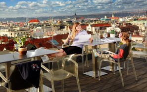 A rooftop terrace with clear views of a cityscape, featuring a table with chairs and a potted plant. - Wenceslas Square Hotel - Czech Leading Hotels (Prague)