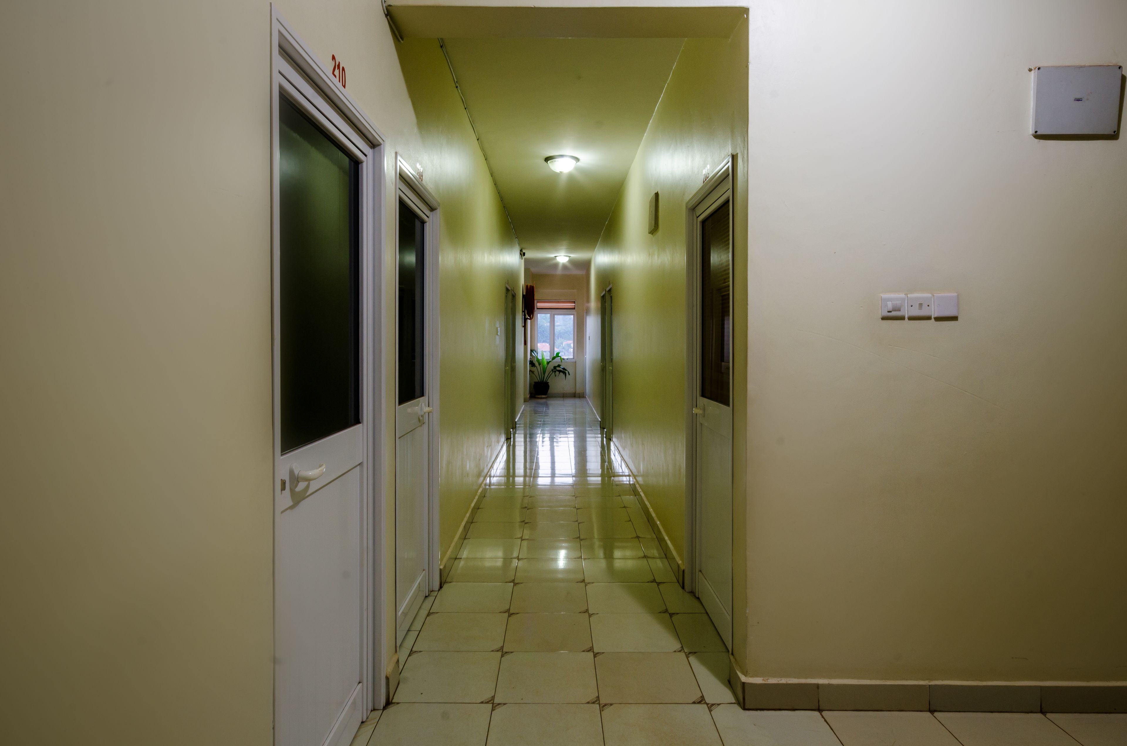 A hallway with a tiled floor and doors on both sides.