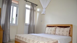 Un dormitorio con cama, cortinas, ventana y puerta.