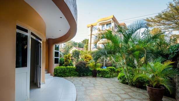 Un patio con suelo de baldosas, plantas en macetas y un edificio con balcón curvo.