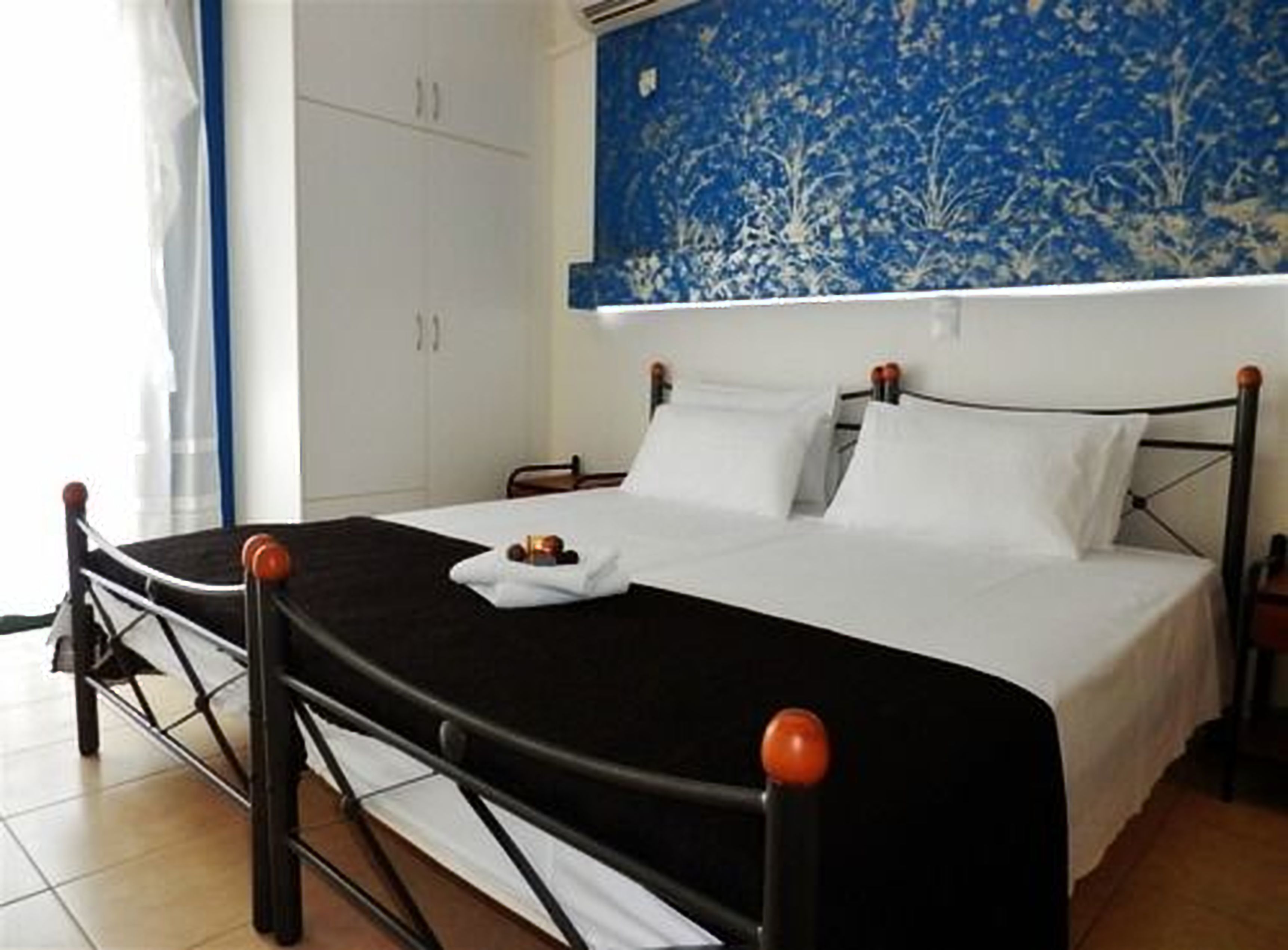 A neatly made bed with a black and white bedspread, a wooden headboard, and a white pillow.