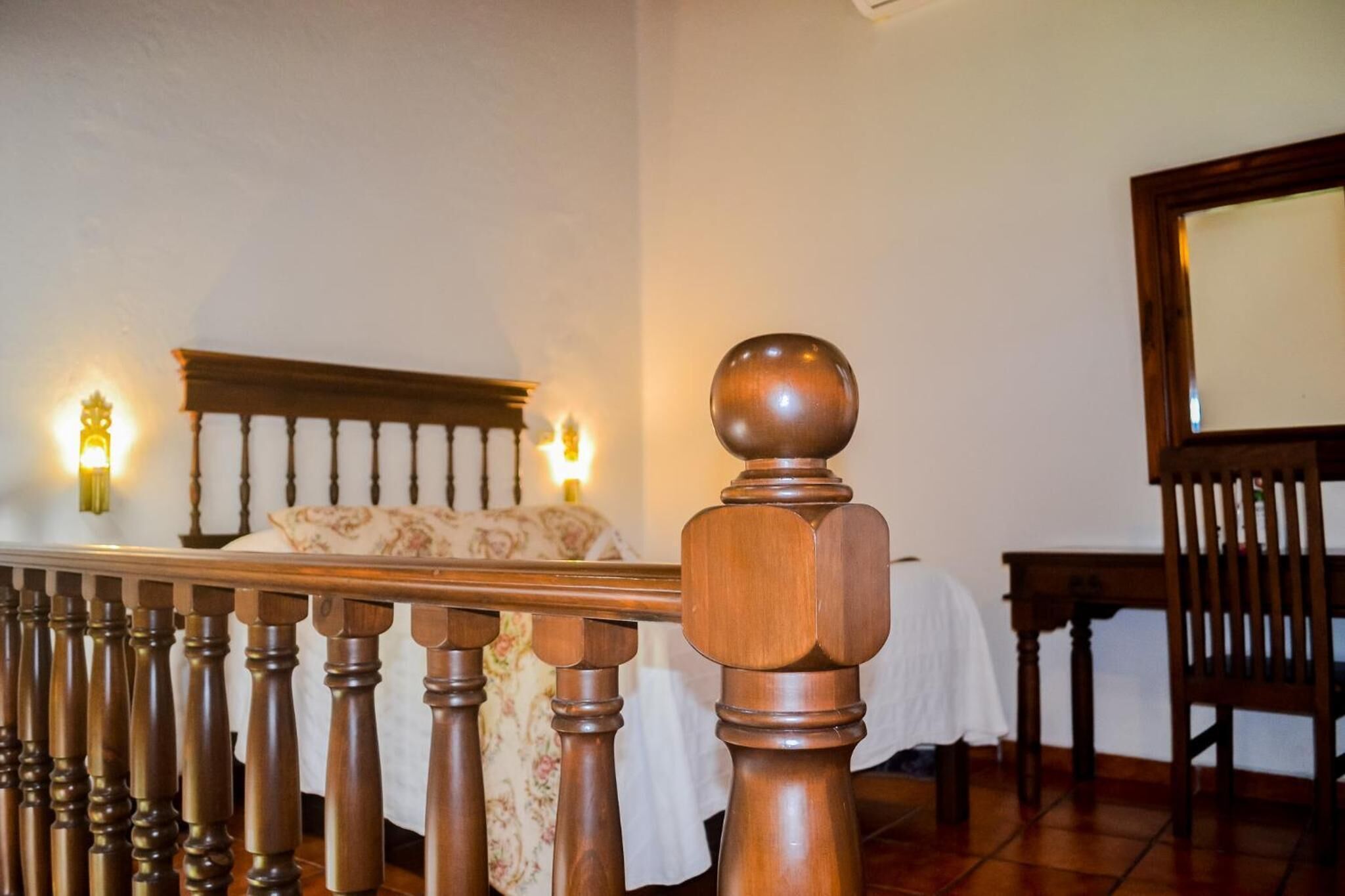 A bedroom with a wooden bed frame, a nightstand, and a chair.