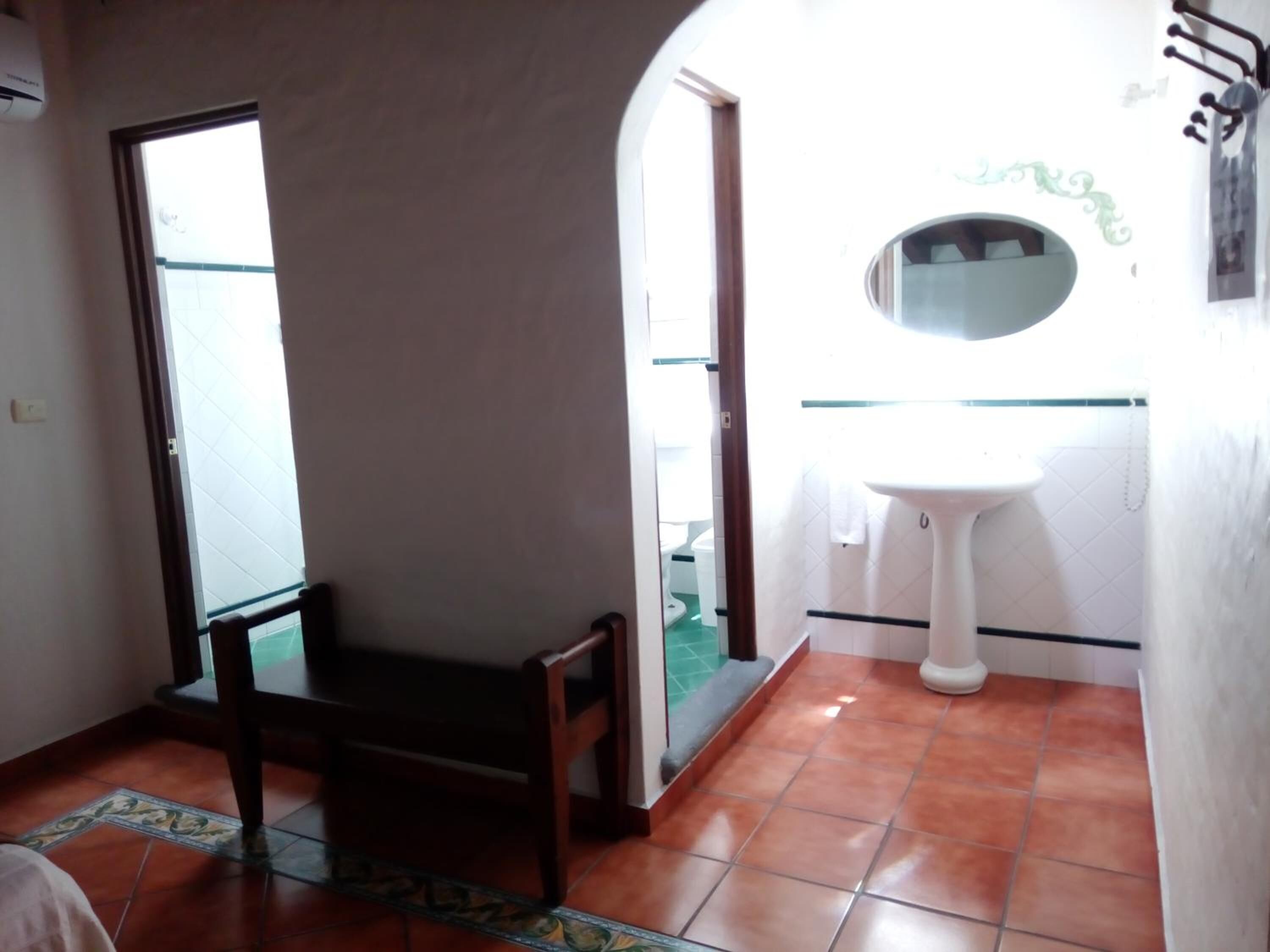 A bathroom with a white sink, a mirror, and a chair.