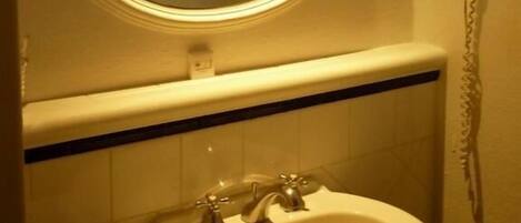 Ein Badezimmer mit rundem Spiegel, Waschbecken und Handtuchhalter.