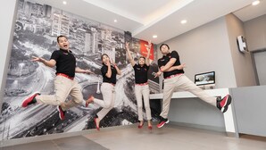 Zona de recepción con un mural de la ciudad, mostrador de recepción y una pantalla que muestra una vista panorámica.