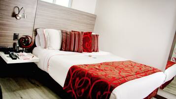 Quarto de hotel com cama, mesa de cabeceira, abajur e espelho.