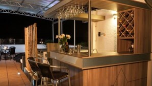 An outdoor bar area with a wooden counter, bar stools, a wine rack, and a glass chandelier. - Isa Victory Hotel Boutique (Armenia)