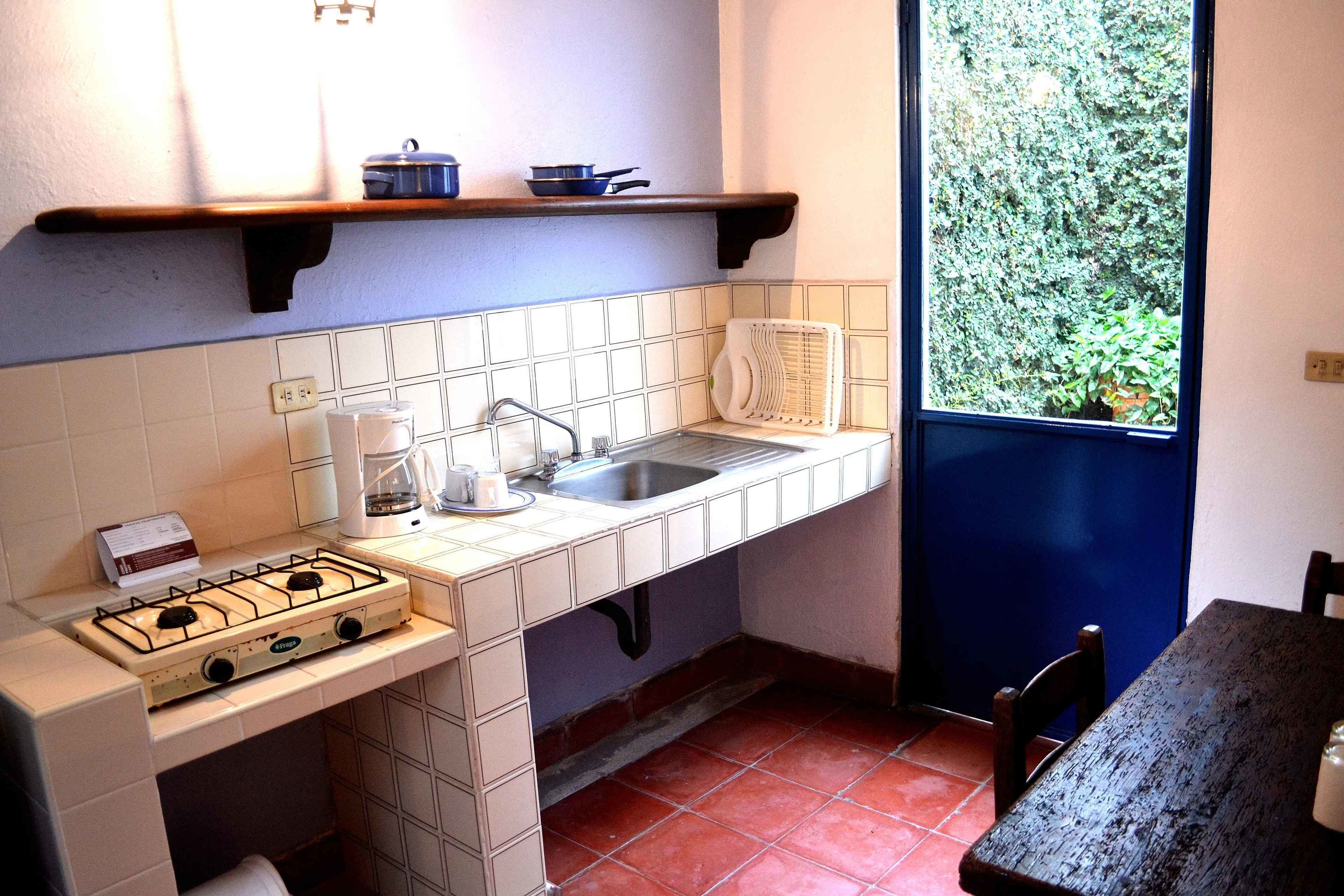 A compact kitchen with a gas stove, sink, and a window overlooking greenery.