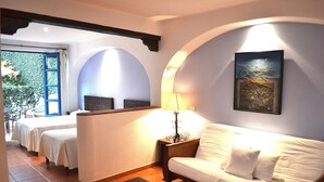 Una habitación de hotel con cama, sofá, lámpara y un cuadro en la pared.