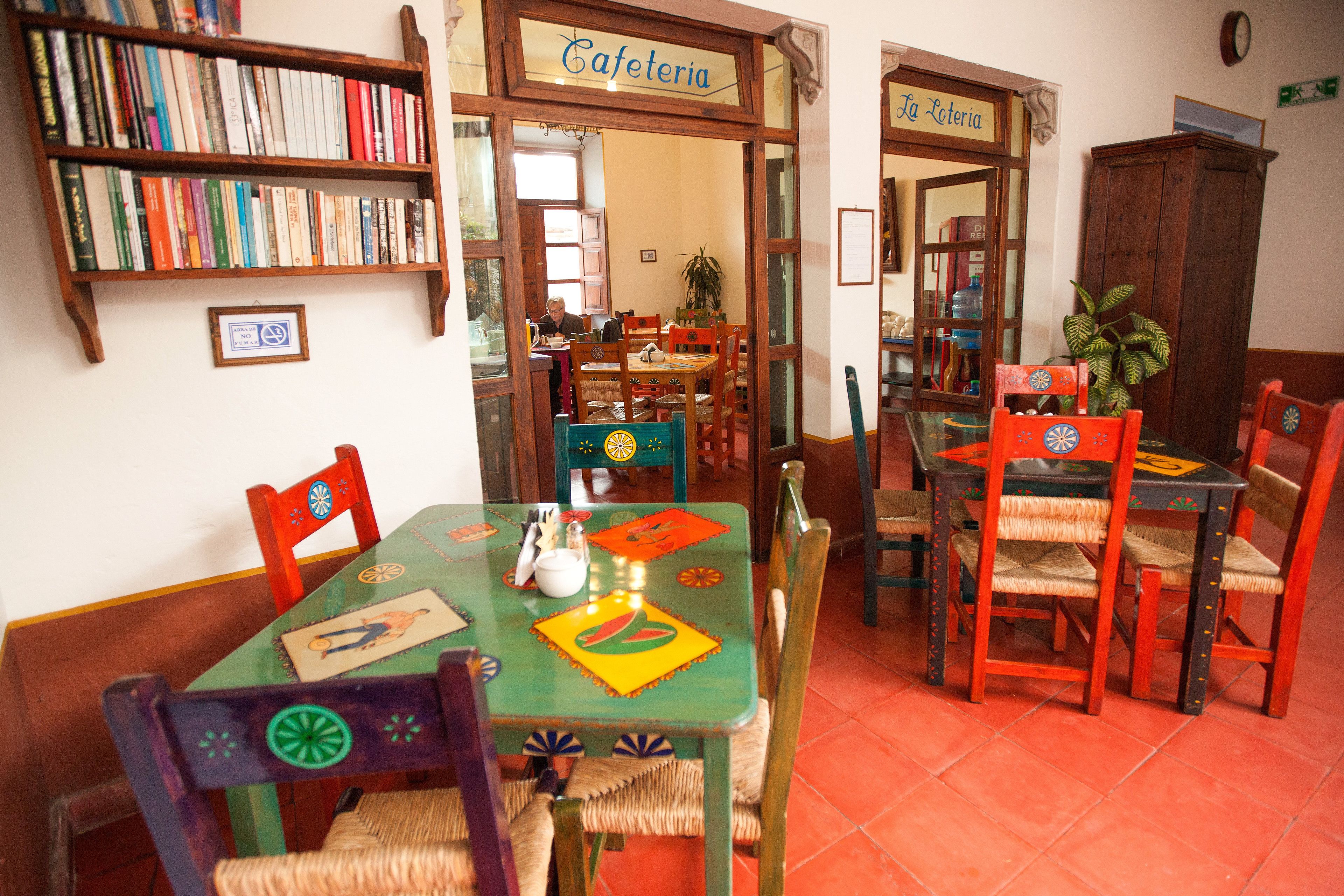 Een eetruimte met een groene tafel, rode stoelen en een boekenkast vol boeken.