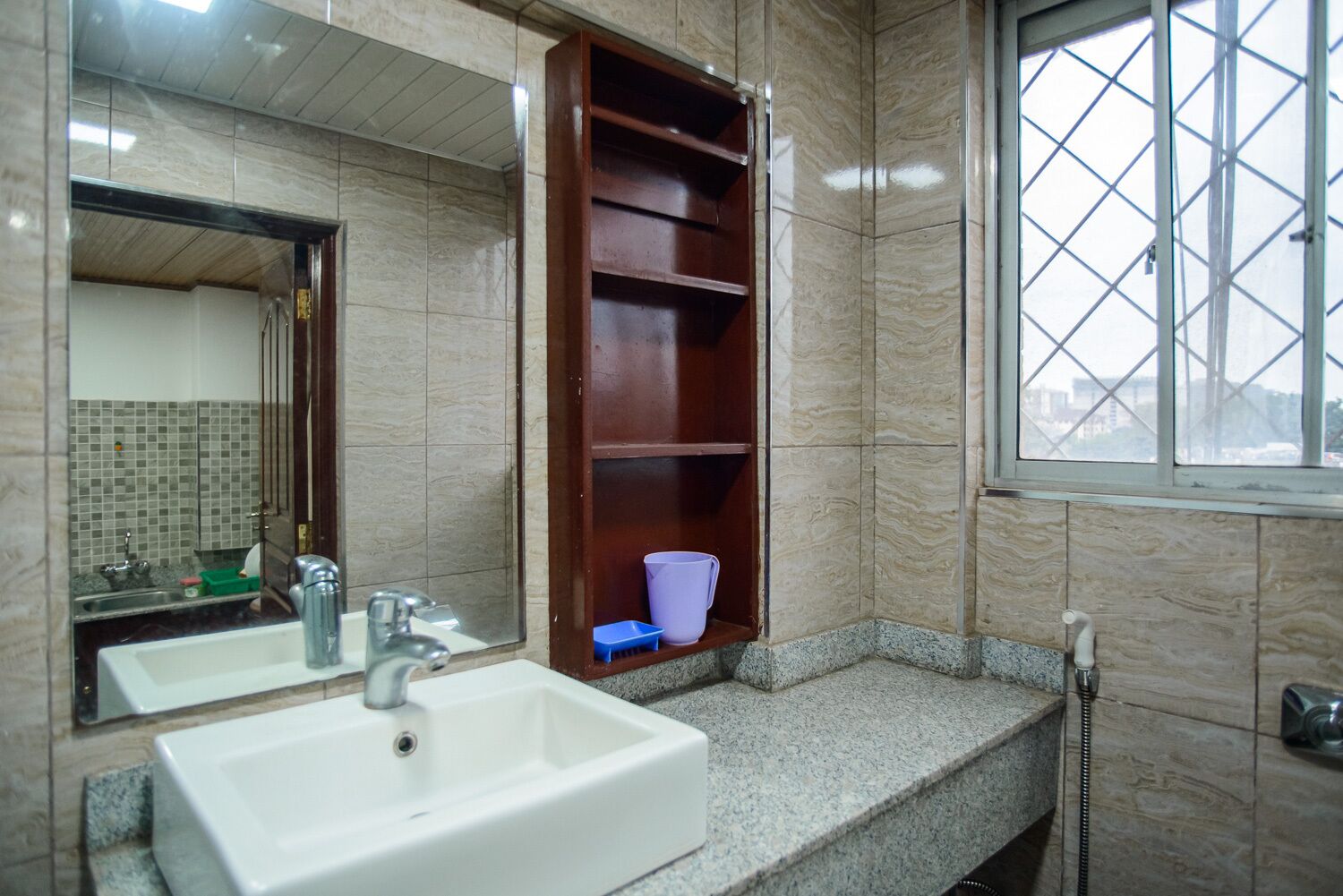 A bathroom with a white sink, a mirror, and a window.