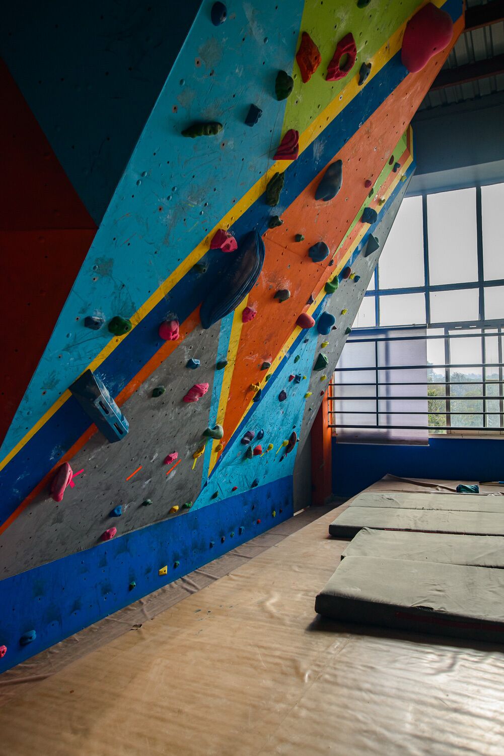 A climbing wall with colorful holds and a window in the background.