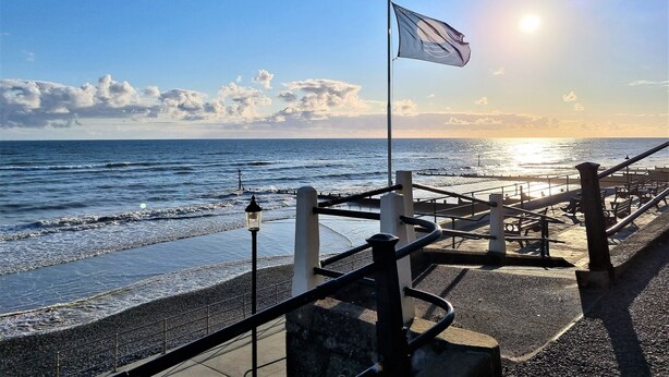 A coastal walkway with a flag, railing, and a lamp post. - Burlington Berties (Sheringham)
