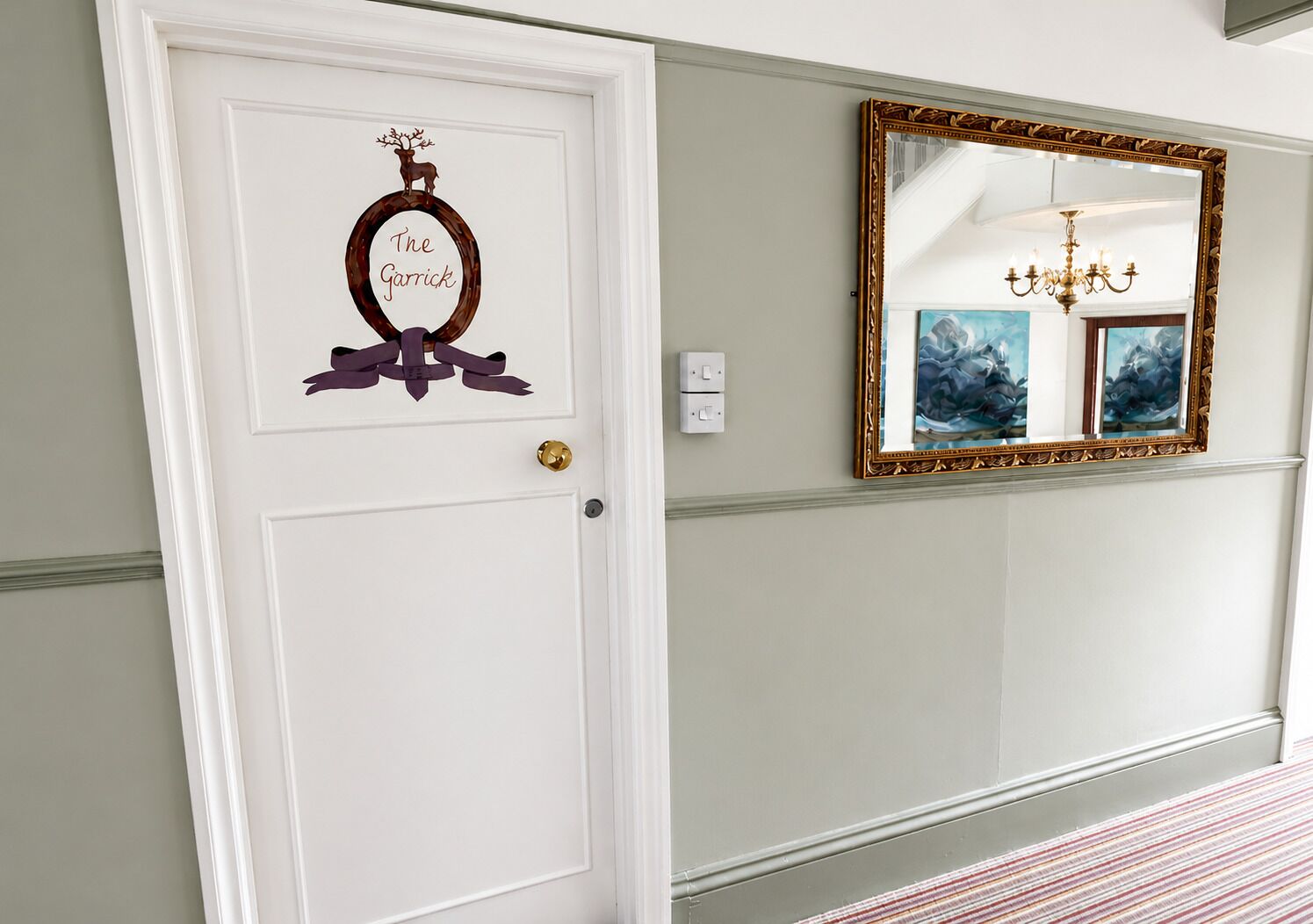 A white door with a decorative wreath and a mirror with a gold frame.
