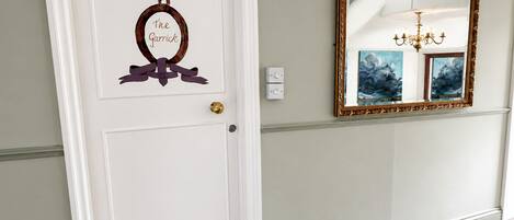 A white door with a decorative wreath and a mirror with a gold frame.