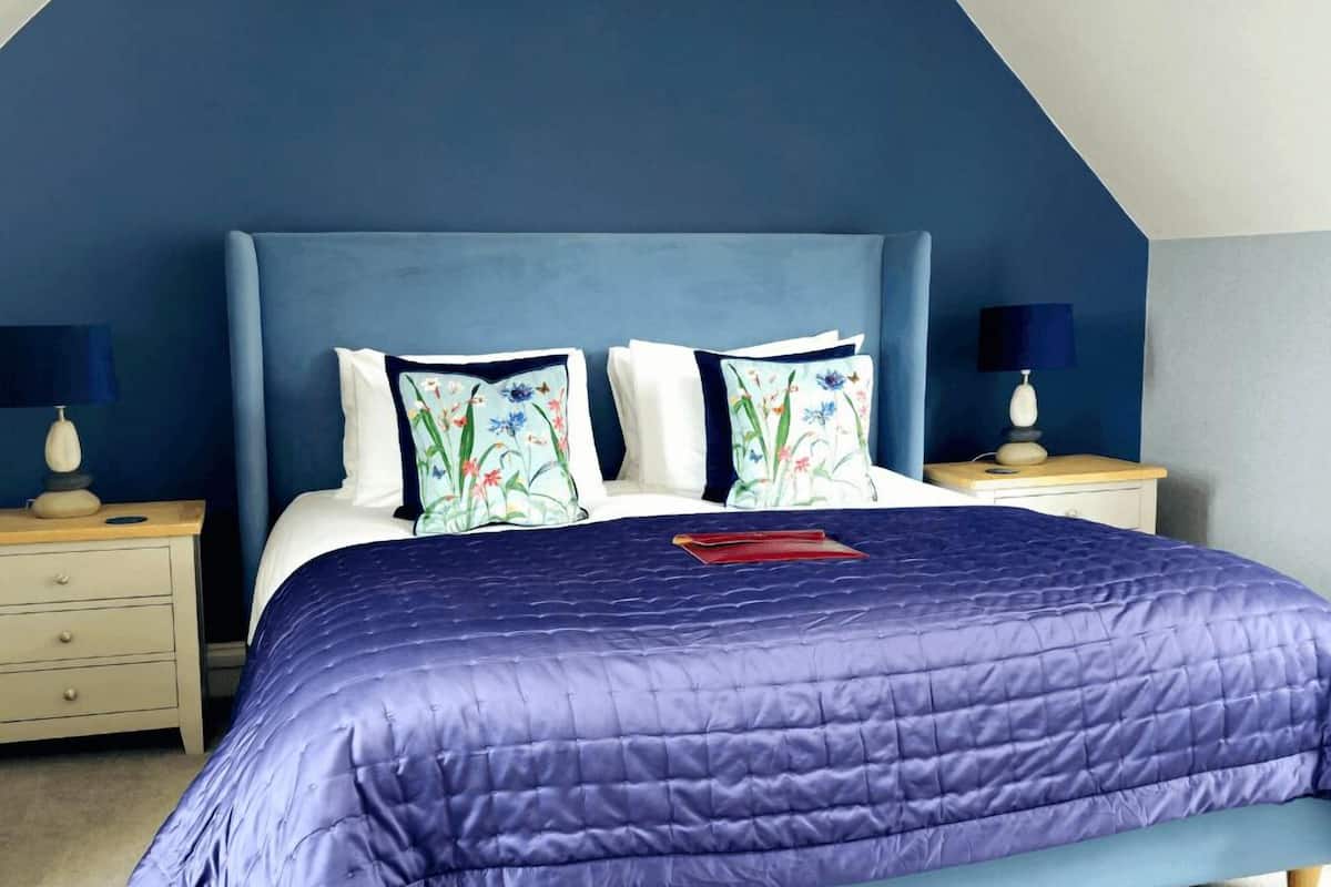 A bedroom with a bed, two nightstands, and a blue headboard.