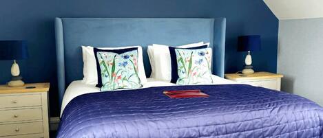 A bedroom with a bed, two nightstands, and a blue headboard.