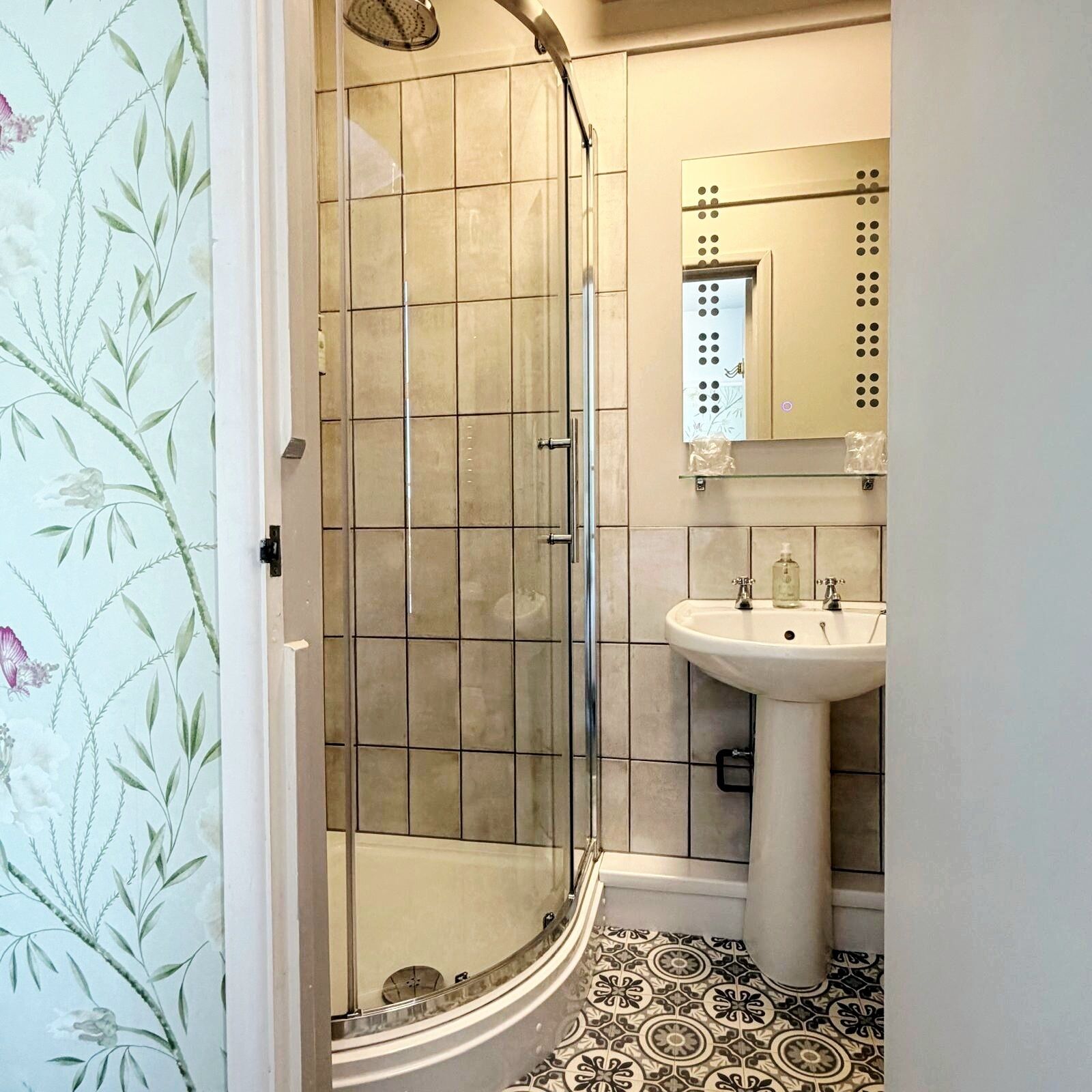 A bathroom with a shower, sink, and mirror.