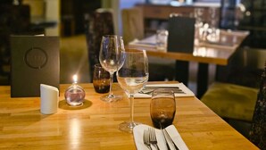 A dining table with wine glasses, a menu, and a candle. - Burlington Berties (Sheringham)