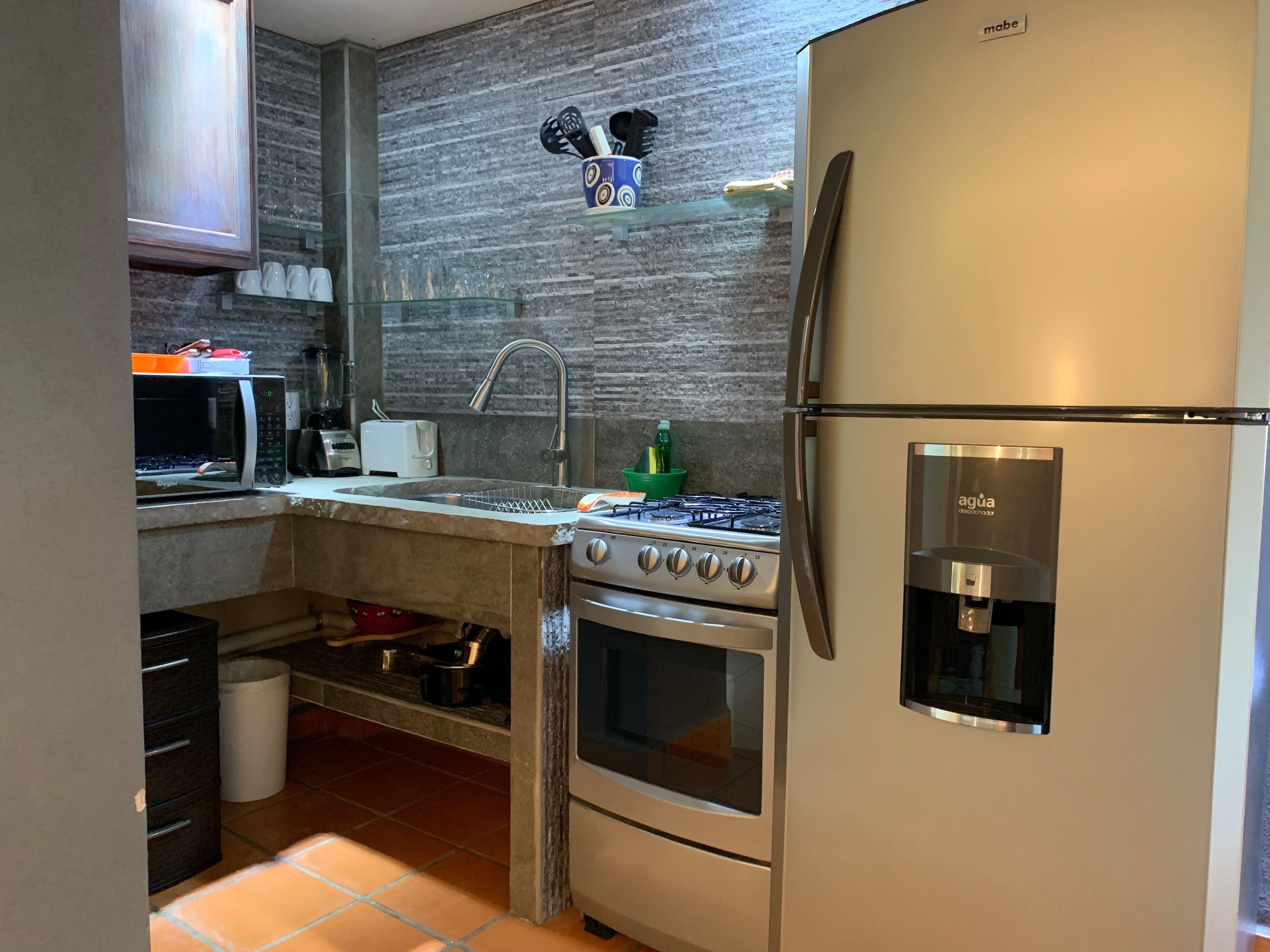 A modern kitchen with a built-in microwave, toaster, sink, stove, and refrigerator.