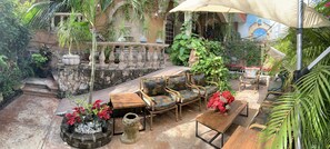 Une terrasse extérieure avec un sol en pierre, des meubles en bois et des plantes en pot.
